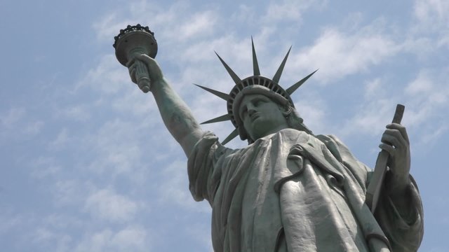 Time lapse of clouds behind the Statue Of Liberty in this shot which says patriotism and patriotic values.