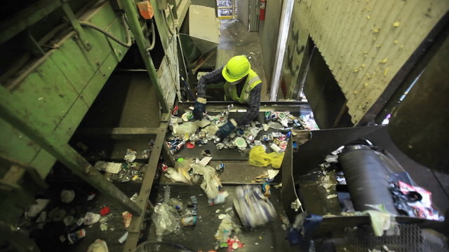 High angle view of workers sorting trash at a recycling center.