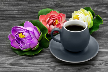 Cup of coffee and artificial colored water lilies