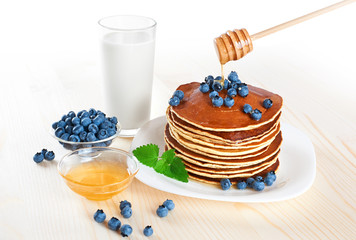 Pancake with blueberries, mint, milk and honey on a white backgr