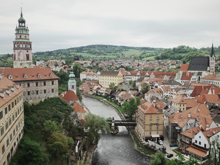 Panoramic view of Cesky Krumlov with plenty of terra cotta roofing-buildings along the river with mountain as background