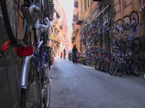 Many bicycles are lined on the street and against the sides of apartment buildings Palermo, Italy.