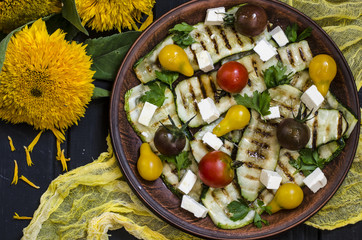 Fototapeta na wymiar Grilled zucchini salad with cherry tomatoes and feta with sunflowers zaprakoy with honey and lime 