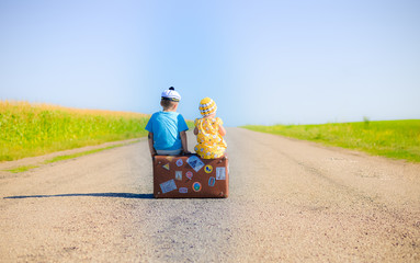 Children on the suitcase over countryside rural road on sunny