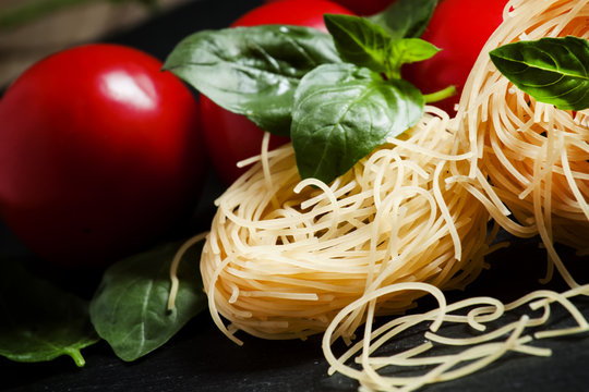 Dry Italian pasta fidellini with basil and tomato, selective foc