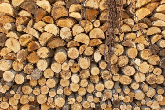 Background of stacked wood. Ready firewood. Various kinds of wooden logs stacked on top of each other. Stack of wood, firewood, background. Dry chopped firewood logs ready for winter.
