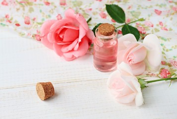 Feminine charming cosmetic products rose perfume fresh flowers pastel pink tones,light wooden surface, soft focus