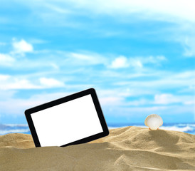 Tablet computer and seashells on the beach with blue sea and sky