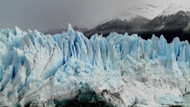 The spiked tops of a glacier stand against rugged mountains.