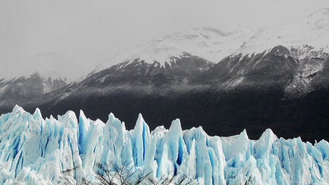 The spiked tops of a glacier stand against rugged mountains.