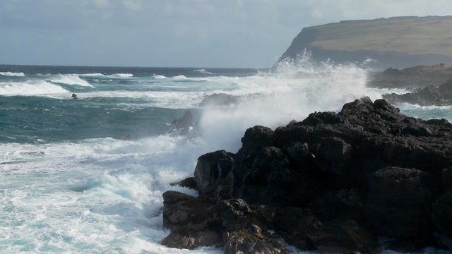 Big waves roll into a tropical island and crash onto the shore.