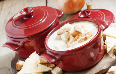 Cheese soup with croutons in red portioned saucepan, selective f