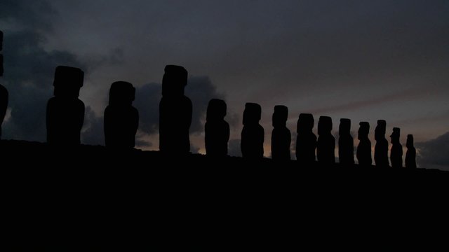 A long line of statues is silhouetted on Easter Island in this time lapse shot.