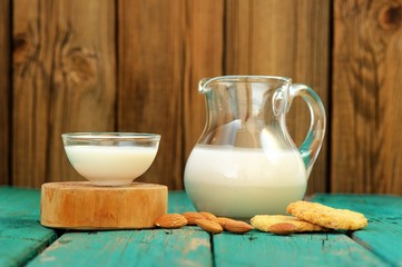 Homemade fresh almond milk in glass jar and glass bowl, with hom