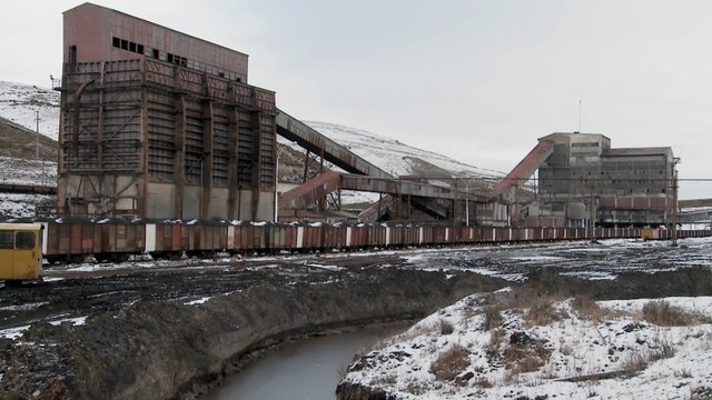 An abandoned mine with ore rail cars in the foreground.