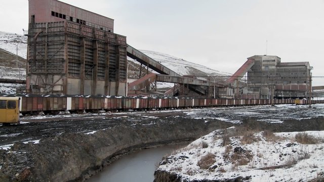 Pan across an abandoned mine with ore rail cars in the foreground.