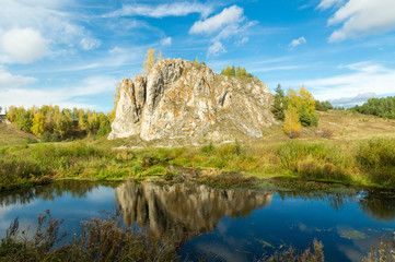 Fototapeta na wymiar пейзаж со скалой возле реки осенним днем