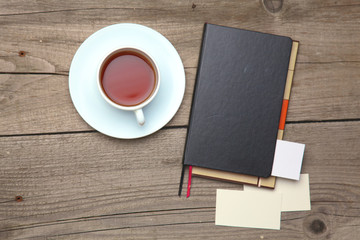 Blank business cards with pen, notebook and tea cup on wooden