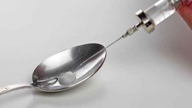 Making drugs. Throwing heroin in spoon and filling syringe with ready liquid drug
