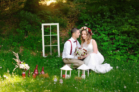 groom and bride sit on the grass in the park