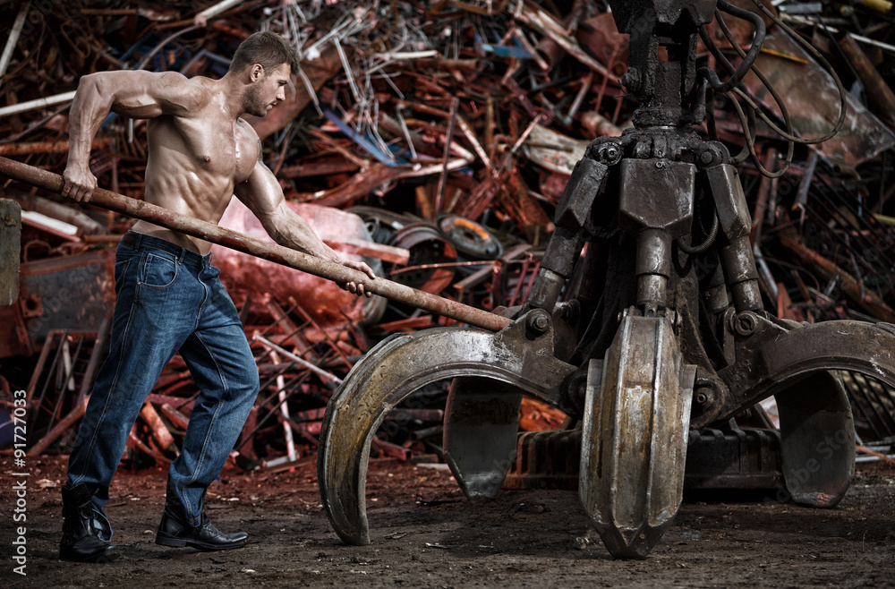 Wall mural muscular man working on junkyard