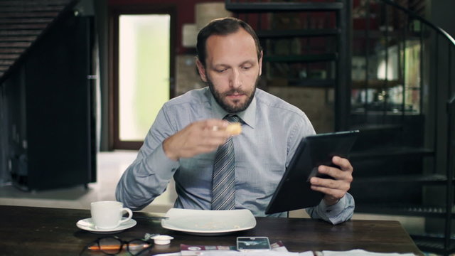 Businessman reading something on tablet computer during breakfast in kitchen
