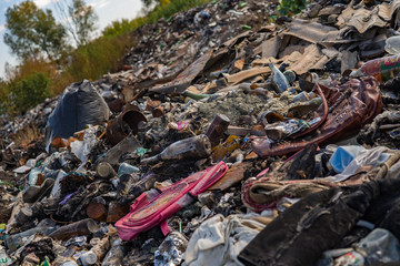 Pile of garbage in front of green trees. Horizon is tilted.