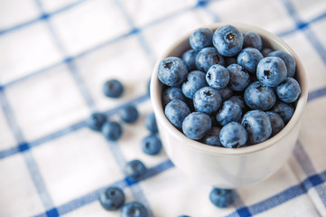 Blueberries in a white bowl on a checkered background