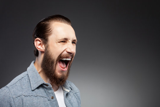 Cheerful young man with beard is expressing anger