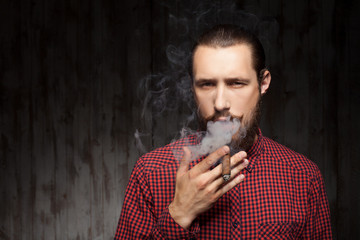 Attractive young bearded man is relaxing with cigarette