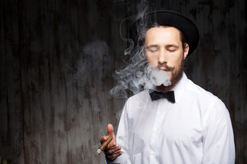 Attractive young bearded guy with hat and cigarette