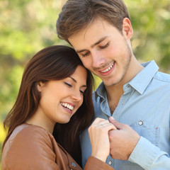 Couple hugging and holding hands while looks an engagement ring