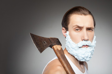 Handsome young hipster guy with beard and hatchet