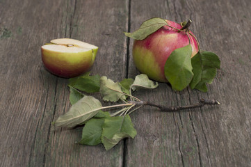 the cut apple and the whole apple with leaves on an old wooden t