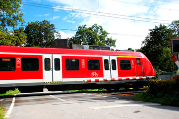 Zug an geschlossenem Bahnübergang mit Schranke, Lok