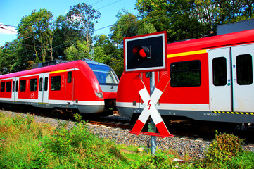 Andreaskreuz mir roter Ampel, dahinter ein Zug