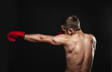 Obraz na płótnie Canvas Athletic bearded boxer with gloves on a dark background
