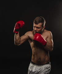Fototapeta na wymiar Athletic bearded boxer with gloves on a dark background