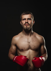 Athletic bearded boxer with gloves on a dark background - 91734030