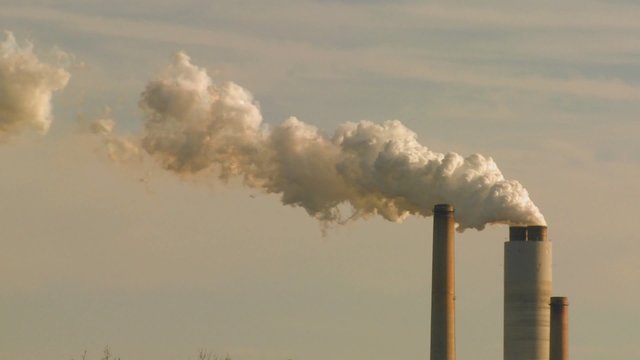 A power plant with smokestacks belches smoke into the air.