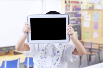 Girl cover her face with tablet in class