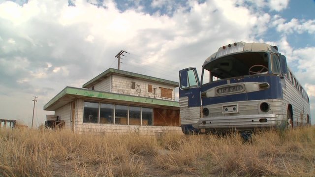A moving time lapse shot of an abandoned Greyhound bus in a field.