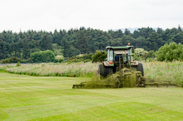 Tractor with grass cutter mowing lawn.