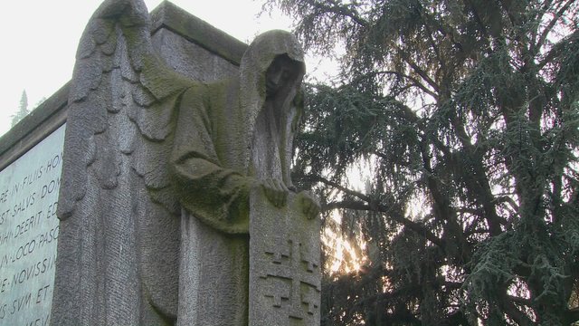 A ghostly angel looks down on a grave from above.