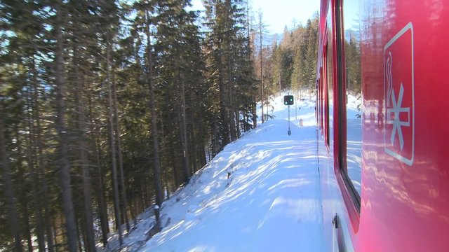 A POV shot from the side of a train as it moves through a snowy landscape.