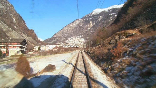 A POV shot from the front of a train moving through a mountainous region.