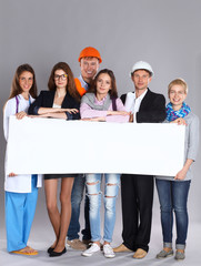 Happy group of people of different professions holding a blank
