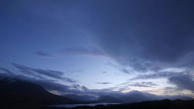 cloudy skies and sunset over loch tulla and rannoch moor in scotland during winter