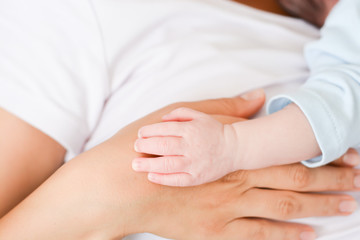 Fototapeta na wymiar Newborn baby holding hand of her mother