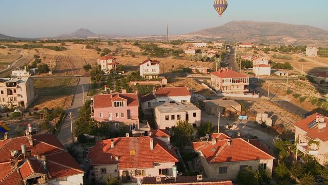 Hot air balloons fly over a neighborhood near Cappadocia, Turkey.